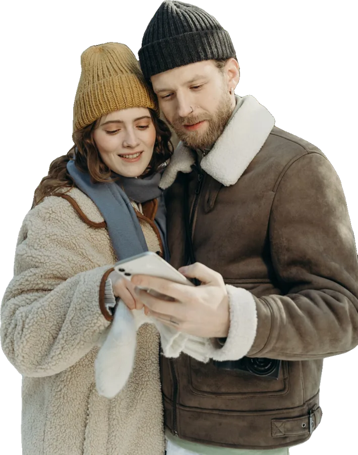 Un couple en manteau d'hiver regarde un téléphone ensemble