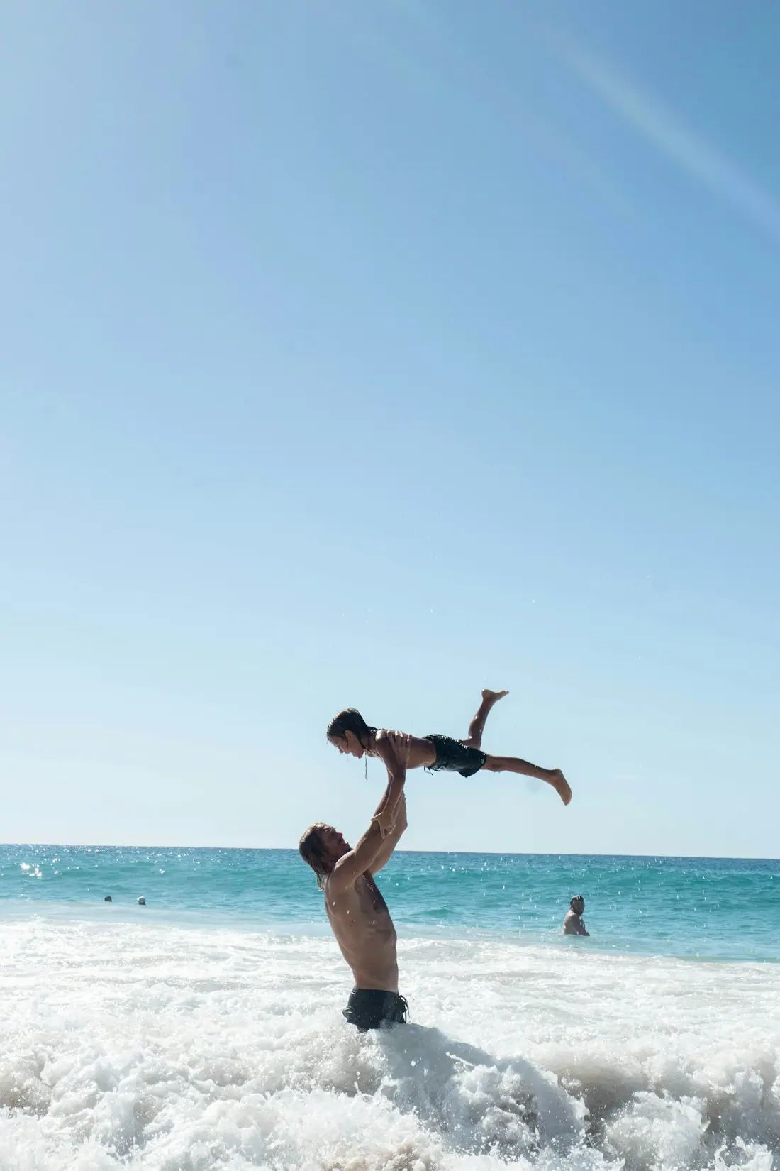 Un père fait sauter son enfant dans la mer